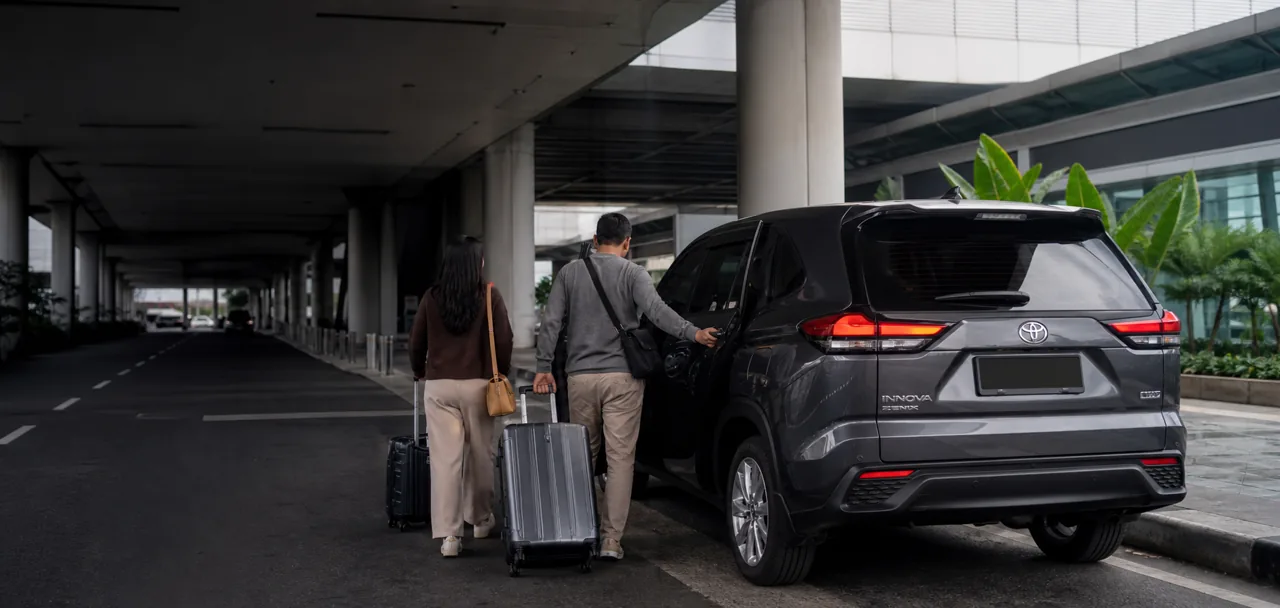 Penumpang dengan koper menuju Toyota Innova Zenix di area antar-jemput bandara